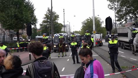 Polizeibarrikade-Beim-Protest-Gegen-Die-Rebellion-Des-Aussterbens-In-Amsterdam,-Bei-Dem-Demonstranten-Und-Polizisten-Still-Auf-Der-Straße-Stehen