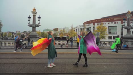 Junge-Studentinnen-Zeigen-Performance-Kunst-Mit-Flügeln,-Die-Bei-Einem-Klimaprotest-Gegen-Das-Aussterben-Der-Rebellion-In-Amsterdam-Aufeinander-Zugehen