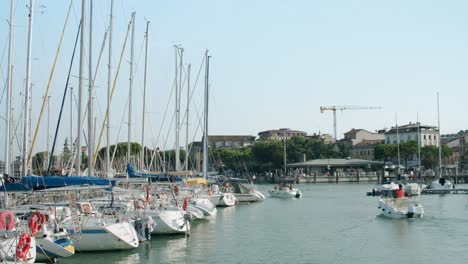 Boats-slowly-entering-Marina-Lake-Garda-that-is-full-of-sailboats