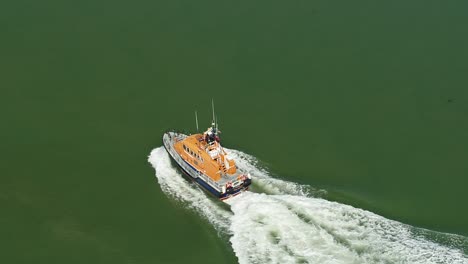 Dramatic-aerial-tracking-shot-of-a-RNLI-Lifeboat-crew-sailing-along-open-water