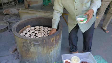 Männerhände-Streuen-Zucker-Auf-Traditionelle-Thailändische-Cupcakes,-Die-In-Einen-Tandoor-Ofen-Gelegt-Werden