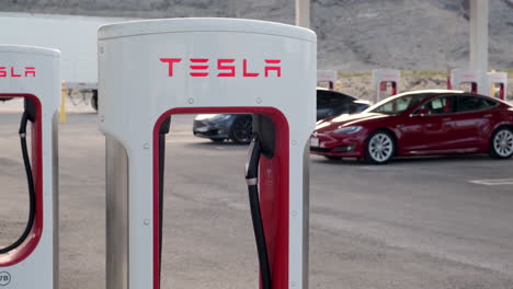 Close-Up-Of-Tesla-Supercharger-With-Tesla's-Charging-In-The-Background