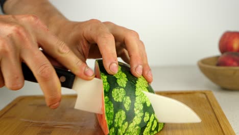 Schneiden-Einer-Saftigen-Wassermelone-Mit-Einem-Keramikmesser-Auf-Einem-Holzschneidebrett