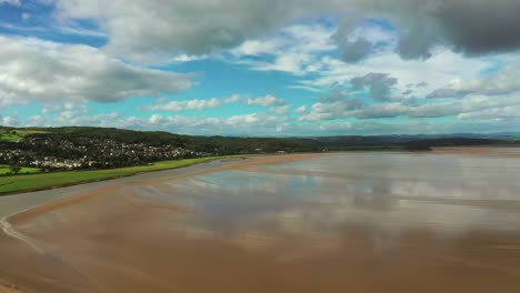 Aerial-rising-shot-over-the-golden-wet-sand-at-low-tide,-on-a-bright-sunny-day