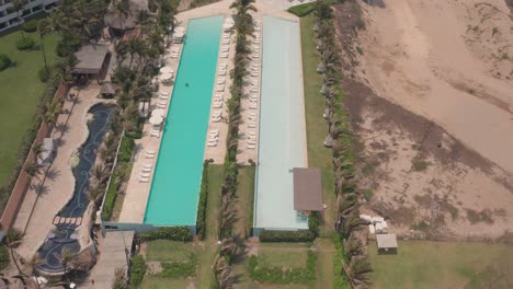 Tilt-Up-Aerial-View-of-Big-Pools-and-Upscale-Luxury-Hotel-Resort-in-Acapulco,-Mexico