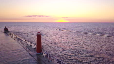 Toma-Aérea-De-Un-Barco-Grande-Que-Pasa-Por-El-Faro-De-Grand-Haven-Al-Atardecer