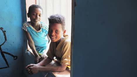 Two-Ziway-local-kids-pose-to-camera-and-smile-while-standing-by-classroom's-window