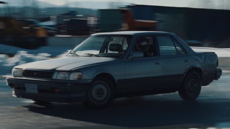 Handheld-shot-of-an-old-car-drifting-in-a-track-during-a-beautiful-winter-morning