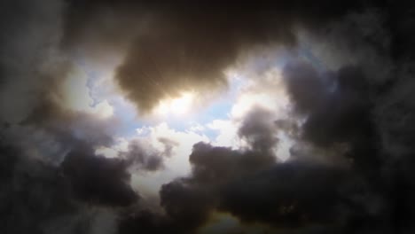 Helle-Strahlen-Der-Sonne-Unter-Den-Dunklen-Wolken-Am-Blauen-Himmel