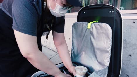 An-unidentified-woman-places-a-drink-order-into-a-Starship-autonomous-delivery-robot-on-the-Oregon-State-University-Campus