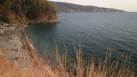 Wide-panning-view-of-small-beach-with-a-bar-on-the-south-end-of-Komiza-on-the-island-of-Vis-in-Croatia