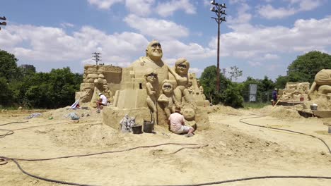 Man-Finishing-The-Incredibles-Sand-Sculpture-At-Sand-Festival-In-Burgas,-Bulgaria---forward-shot