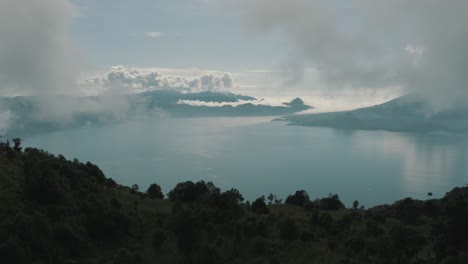 Drone-aerial-view,-flying-over-trees,-revealing-beautiful-blue-lake-Atitlan,-Guatemala