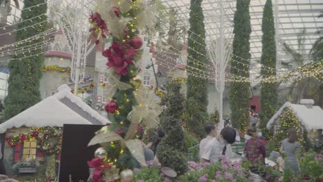 Exposición-De-Navidad,-Deseos-De-Poinsettia-En-La-Cúpula-De-Flores-De-Singapur-Con-Turistas-Con-Mascarillas-Paseando---Plano-General