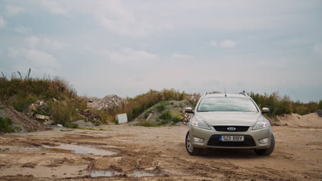 Front-view-of-gray-Ford-Mondeo-stopped-in-front-of-demolition-waste-humps