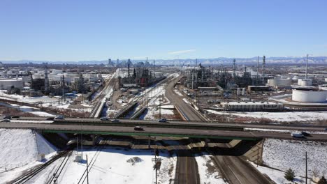 The-aerial-view-moves-back-to-show-a-Refinery-and-highway-with-Downtown-Denver-and-mountains-in-the-background