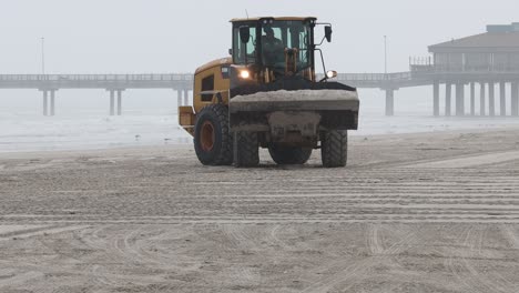 Cargadora-De-Ruedas-Caterpillar-De-930-M-Moviendo-Un-Balde-De-Arena-En-La-Playa-White-Cap-En-North-Padre-Island-En-Una-Mañana-Nublada