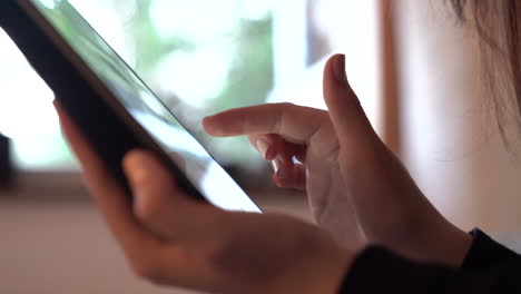 Handheld-Nahaufnahme-Der-Hände-Einer-Frau-Mit-Einem-Tablet,-Das-Auf-Dem-Touchscreen-Scrollt