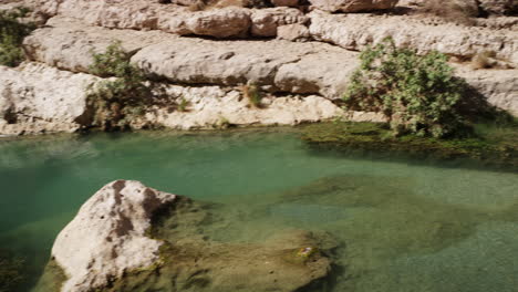 Sunny-day-at-the-turquoise-pools-of-Wadi-Shab-canyon,-Oman,-wide-shot-pan-right