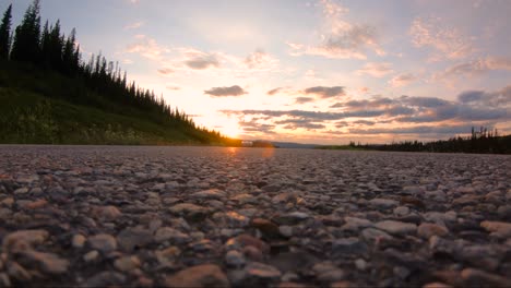 A-white-sports-car-seen-driving-on-the-road-runs-overtop-of-camera-sitting-on-road-surface