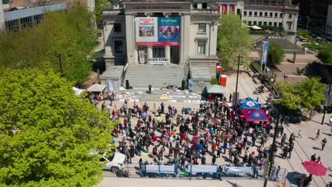 Anti-mask-rally-in-a-public-square,-aerial-slow-dolly-in