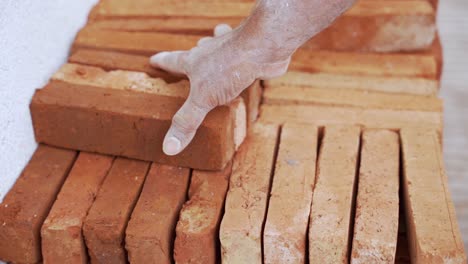 Hand-grabbing-bricks-for-building-wall,.-Close-up