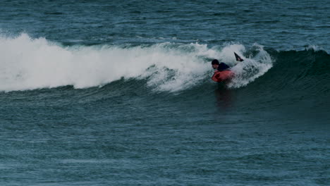 Surfista-Disfrutando-De-Una-Poderosa-Ola-Oceánica-A-La-Distancia