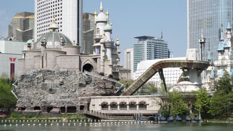 People-riding-a-roller-coaster-in-Lotte-World-amusement-park-in-Jamshil-Seoul-South-Korea-view-from-near-Seokchon-lake-wide-angle