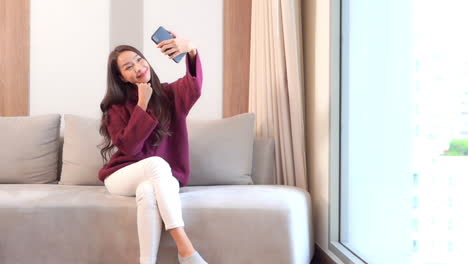 Beautiful-Exotic-Woman-Taking-Selfie-Photo-With-Smartphone-Camera-in-Privacy-of-Living-Room-on-Natural-Light,-Full-Frame-Slow-Motion