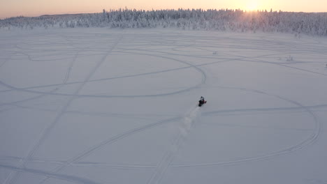 Tiro-De-Drone-De-Una-Moto-De-Nieve-En-Un-área-Abierta-De-Nieve-En-El-Bosque-Durante-Una-Fría-Temporada-De-Invierno-En-Suecia