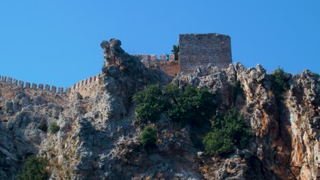 Sea-view-of-ruins-of-old-fortress-wall-Alanya-in-sunny-summer-day,-clear-blue-sky,-medium-handheld-shot