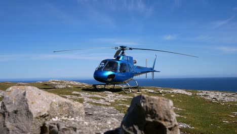 Privater-Tourhubschrauber-Auf-Dem-Gipfel-Einer-Bergklippe-Mit-Blick-Auf-Die-Blaue-Ozeanlandschaft,-Die-Sich-Langsam-Rechts-Auf-Den-Start-Vorbereitet