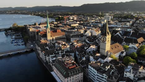 Aerial-view-of-Zurich,-Switzerland-at-sunset-by-the-river-Limmat-with-views-of-St
