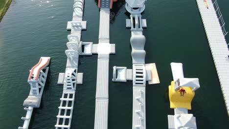 People-enjoying-a-sunny-day-at-Hong-Kong-core-aqua-park-floating-fun-slides,-Aerial-view