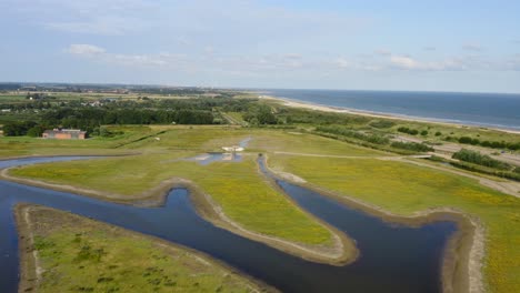 Aerial-backward-shot-over-the-Waterdunes---a-nature-area-and-recreational-park-in-the-province-of-Zeeland,-The-Netherlands