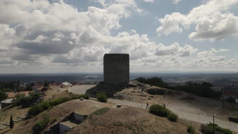 Visitors-walking-towards-Castle-of-Guarda,-hilltop-keep-landmark