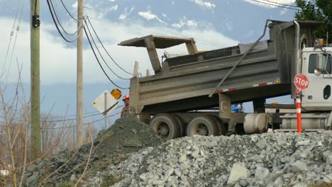 El-Camión-Vuelca-El-Suelo-Siguiendo-Las-Instrucciones-De-Un-Trabajador-Con-Chaleco-Reflectante,-La-Excavadora-Levanta-La-Carga