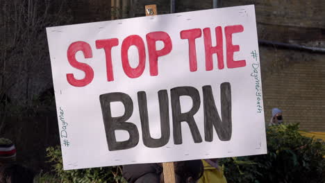 A-handmade-cardboard-placard-is-held-up-that-reads,-“Stop-the-burn”-at-a-protest-opposing-a-new-waste-incinerator-at-Edmonton