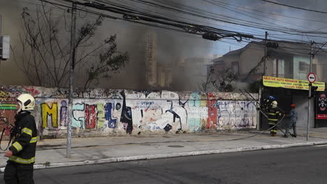 Bombero-Sube-La-Escalera-Para-Acceder-Al-Fuego-Urbano-Humeante-Detrás-De-Un-Muro-De-Hormigón,-En-La-Avenida-Tereza-Cristina,-Distrito-De-Ipiranga