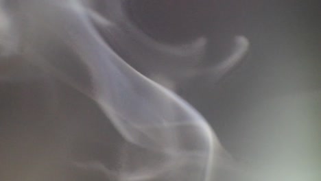 White-smoke-slowly-floating-through-space-against-dark