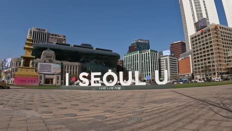 "I-Seoul-U"-sign-in-front-of-City-Hall-Government-building-with-Seoul-cityscape-in-the-background,-South-Korea