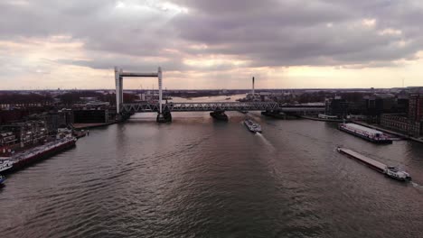 Antena-Sobre-Oude-Maas-Con-Barcos-Que-Se-Acercan-Al-Puente-Ferroviario-Spoorbrug-Contra-El-Cielo-Del-Atardecer-En-Dordrecht