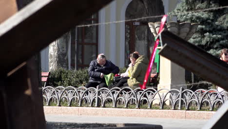 Women-sit-talking-on-a-bench-behind-tank-traps-made-from-welded-steel-metal-girders-during-the-Russian-invasion-of-Ukraine