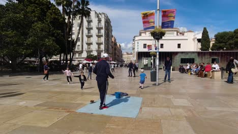 Male-street-performer-using-string-to-create-soap-bubbles-and-plays-with-kids