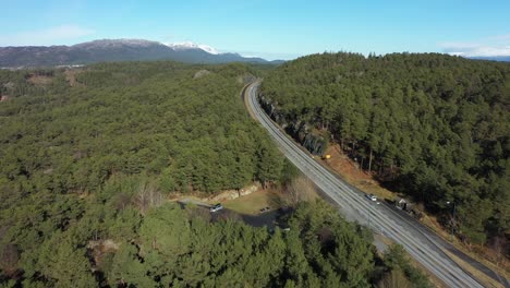 E39-coastal-highway-going-through-green-forest-on-Stord-Island-close-to-digernessundet-and-bomlo-bridge---Aerial-perspective