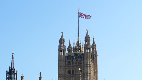 Britische-Gewerkschaftsflagge-In-Zeitlupe-über-Dem-Berühmten-Victoria-Tower,-Blauer-Himmel