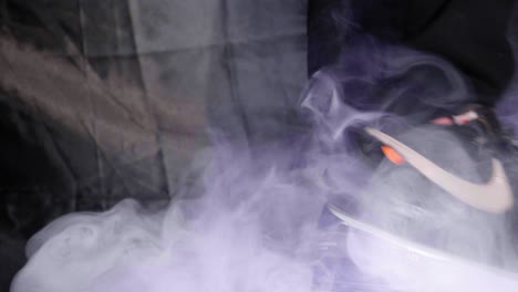 Low-close-up-shot-of-person-standing-in-black-Nike-shoes-with-smoke-in-a-dark-dramatically-lit-room-with-black-background