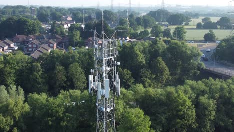 Antena-De-Torre-De-Radiodifusión-5g-En-El-Campo-Británico-Con-Vehículos-Que-Viajan-En-El-Fondo-De-La-Carretera-Vista-Aérea-Ascendente