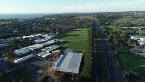 Smooth-reveal-of-Mornington,-Victoria-suburb-and-local-high-school-looking-out-over-the-beautiful-bay-behind