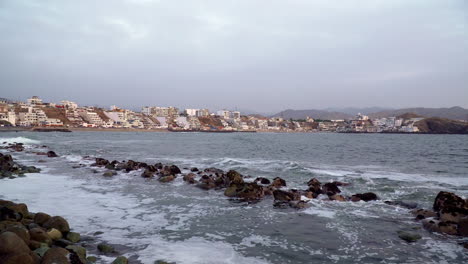 Still-shot-of-waves-hitting-the-rocks-by-the-beach-in-San-Bartolo,-Lima,-Peru